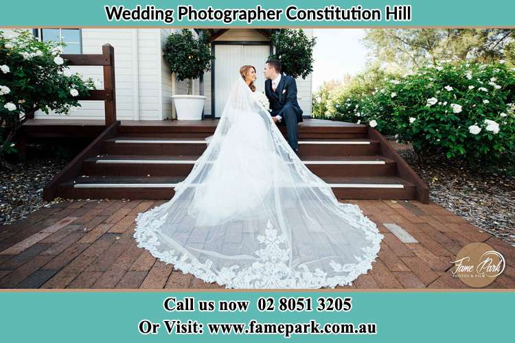 Photo of the Bride and the Groom looking each other while sitting at the staircase Constitution Hill NSW 2145